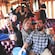 A tour group laughing and smiling while sitting in overstuffed chairs and holding up a variety of beverages inside a rail car
